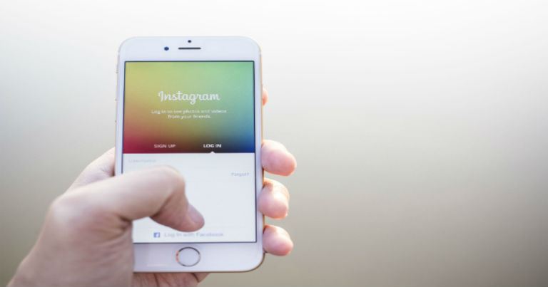 person's hand holding a phone on the instagram sign-on screen