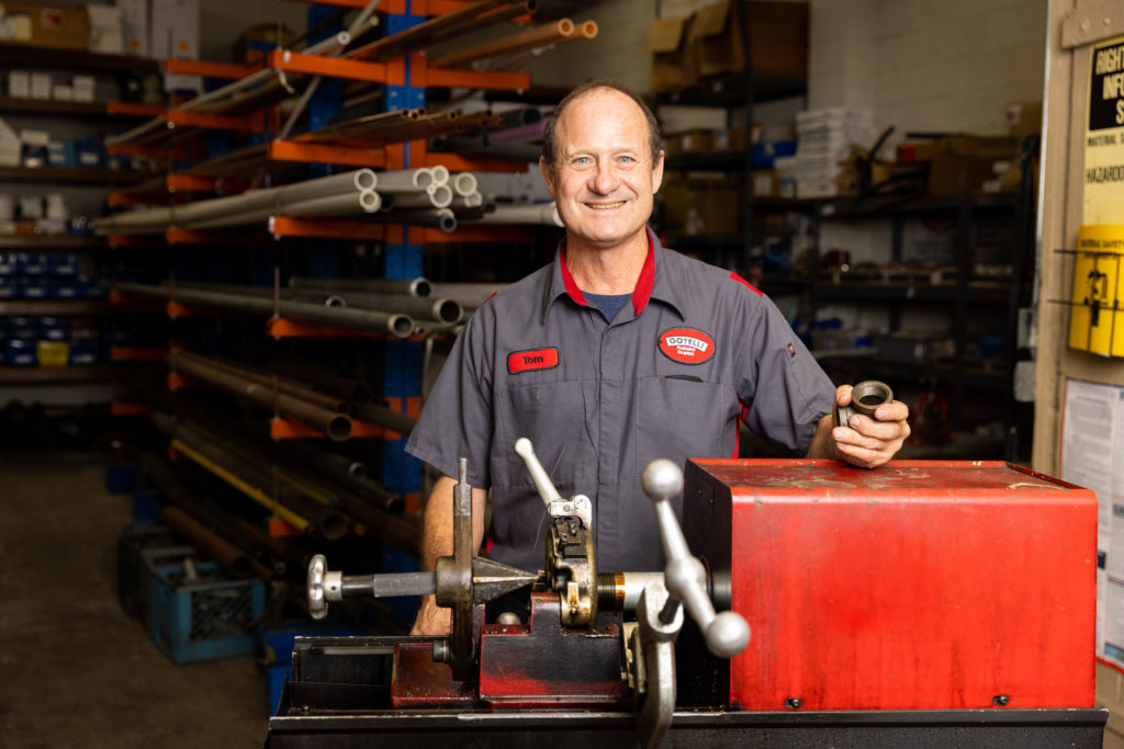 friendly Gotelli plumber smiling for the camera while standing inside their workshop