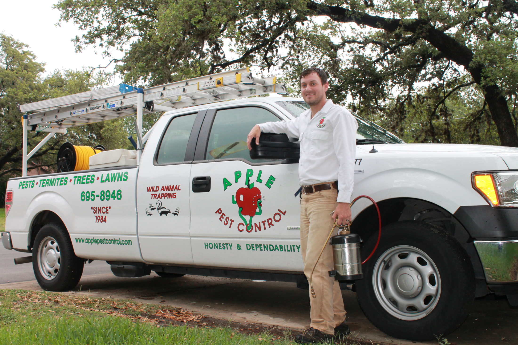 friendly apple pest control technician standing next to company truck