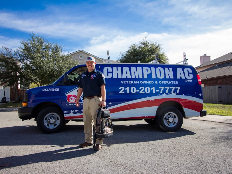 friendly ac technician wearing champion ac uniform, standing beside champion ac red and blue van