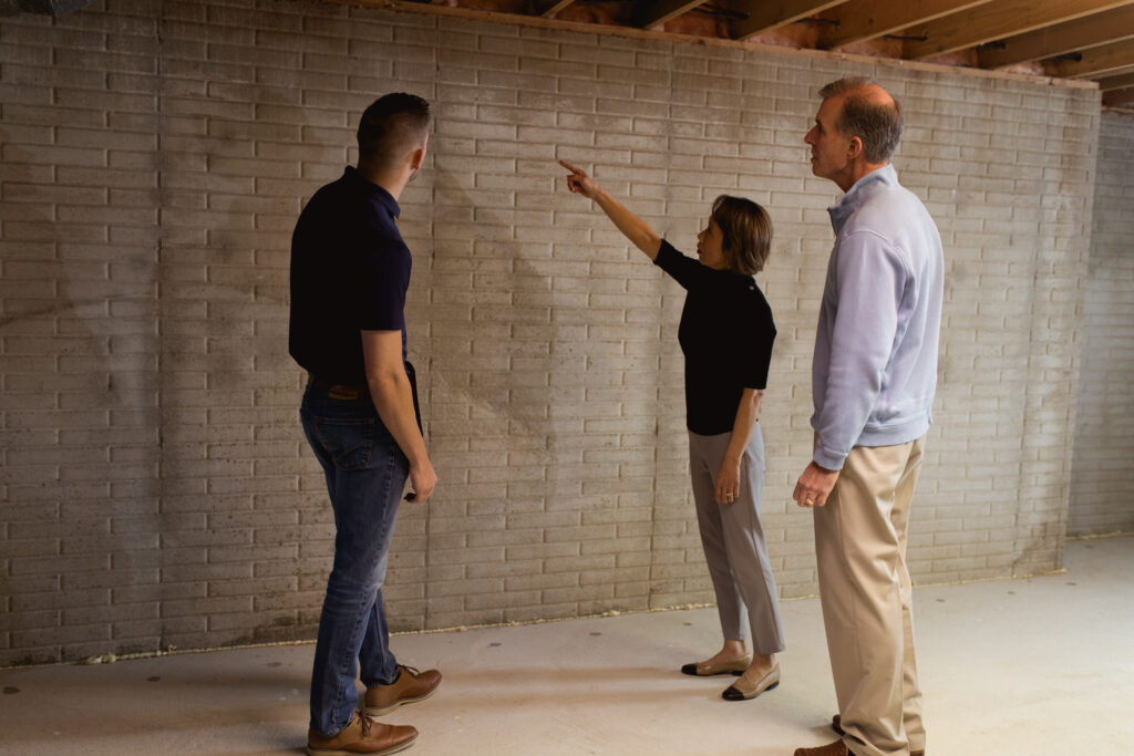 two foundation repair expert assessing a womans basement for damage